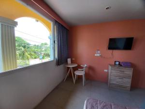 a room with a window and a table and a tv at In Phuket House in Phuket Town