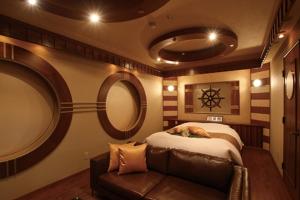 a bedroom with a bed and a couch in it at HOTEL ALPHA - Adult Only in Kaminoyama