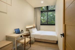 a bedroom with a bed and a desk with a laptop at Alma House in Singapore