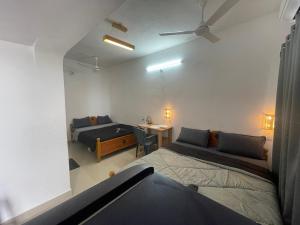 a room with two beds and a desk and a bed at Caribbean Island Home Stay in Mahabalipuram