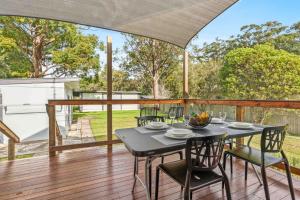 a patio with a table and chairs on a deck at Jack's Beach Shack by Experience Jervis Bay in Huskisson