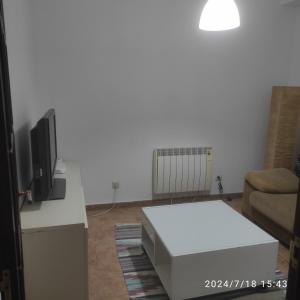 a living room with a white table and a tv at Apartamento A Coruña in Oleiros