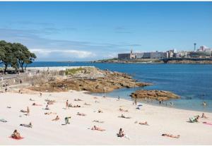 a group of people on a beach near the water at Apartamento A Coruña in Oleiros