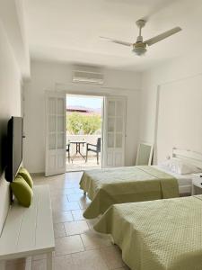 a bedroom with two beds and a patio with a table at Villa Telendos in Telendos +82 photos