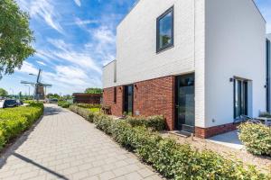 een bakstenen gebouw met een windmolen op de achtergrond bij Roosjesweg 2 Gastenkamer met parkeerplaats en terras EG in Domburg