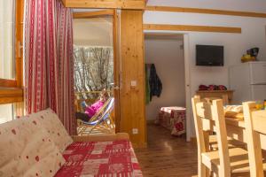 een woonkamer met een tafel en een persoon in een stoel bij Résidence Goélia Le Balcon des Neiges in Saint-Sorlin-dʼArves