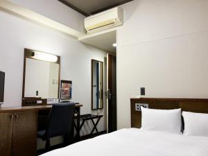 a bedroom with a bed and a desk and a mirror at Hotel Route-Inn Seki in Sekimachi