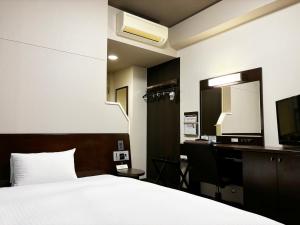 a bedroom with a bed and a desk and a mirror at Hotel Route-Inn Seki in Sekimachi