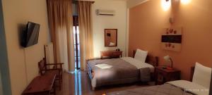 a hotel room with two beds and a television at IZEΛA Hotel in Kala Nera