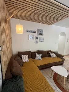a living room with a brown couch and a table at Appartement 5 personnes avec espace plein air in Saint-Maurice-sur-Moselle