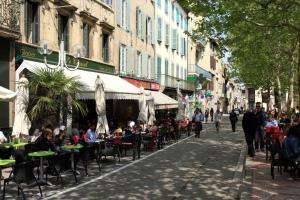 eine Straße mit Tischen und Stühlen und Menschen, die an Tischen sitzen in der Unterkunft Résidence Armagnac - City Center in Carcassonne