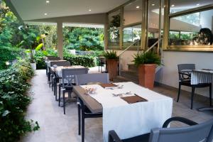 a restaurant with white tables and chairs and windows at Park Hotel Giusy in Lido di Camaiore