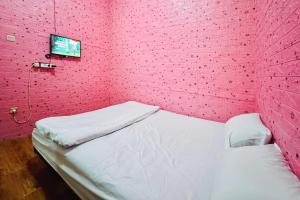 a pink room with a bed and a tv at Penginapan Dison RedPartner in Bekasi +10 photos