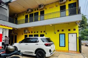 a white truck parked in front of a yellow building at Penginapan Dison RedPartner in Bekasi