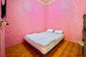 a bedroom with a pink wall with a bed in it at Penginapan Dison RedPartner in Bekasi