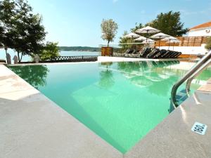 a swimming pool with blue water and umbrellas at Olive Villas Beach Hotel in Sozopol