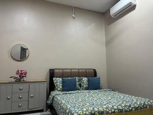 a bedroom with a bed and a dresser and a mirror at AR Homestay Bukit Kuang Kemaman in Cukai