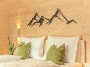 a bed with white pillows and a wooden wall at Haus Becken in Sankt Jakob in Defereggen