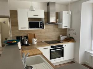 eine Küche mit weißen Schränken und einer Arbeitsplatte in der Unterkunft Les Chamois du Sancy in Le Mont-Dore