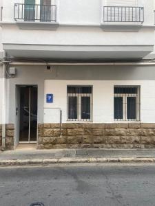 - un bâtiment blanc avec des fenêtres et une porte dans l'établissement Pensión Alicante Bergez, à Alicante
