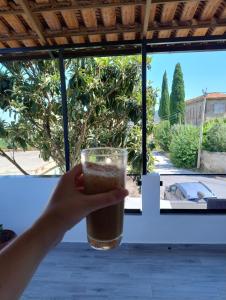 a hand holding a glass of coffee in front of a window at Vila Kurti in Vlorë