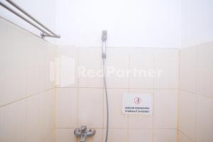 a bathroom with a shower with a sign on the wall at Griya Jasmine Syariah Seturan RedPartner in Yogyakarta