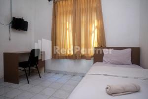 a bedroom with two beds and a desk and a window at Griya Jasmine Syariah Seturan RedPartner in Yogyakarta