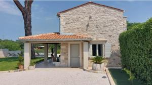 a small stone building with a door in a driveway at VILA ŠKARLANIJA, Umag in Umag