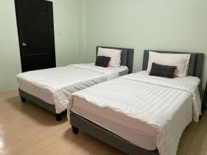 two beds in a room with white sheets at Baan Ploy In in Chiang Mai