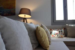 a living room with a couch with pillows and a lamp at Antigoni Villas in Gavrio