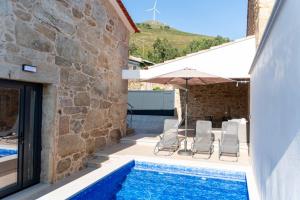 a pool with chairs and an umbrella next to a building at Guest House Taião in Valença