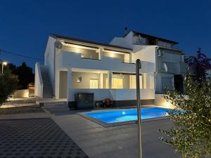 Una casa blanca con piscina por la noche. en Lux Apartments Villa Navalia, en Novalja