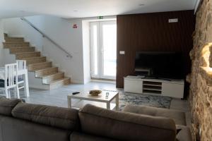 a living room with a couch and a tv at Guest House Taião in Valença