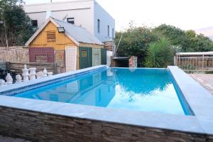 a swimming pool with a house in the background at Foundation Stones Lodge in Paarl
