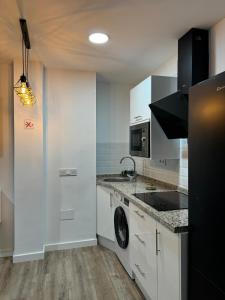 a kitchen with white cabinets and a washer and dryer at Linerlife in Málaga