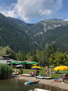 a group of people sitting under umbrellas near a body of water at Appartment Isabelle Sky in Presseggersee