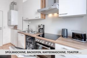 a kitchen with white cabinets and a stove top oven at NEU Easy Sleep - FeWo mit 3 Zimmern bis 6 Personen, 5 Einzelbetten oder 2 Doppelbetten und 1 Schlafcouch, Küche, Tageslichtbad - Monteure willkommen in Bayreuth +6 photos