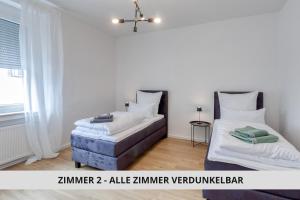 two beds in a room with white walls at NEU Easy Sleep - FeWo mit 3 Zimmern bis 6 Personen, 5 Einzelbetten oder 2 Doppelbetten und 1 Schlafcouch, Küche, Tageslichtbad - Monteure willkommen in Bayreuth