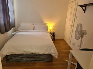 a white bed in a room with a fan at 4Br-2Ensuite-10minCentralLondon-Sleeps11-Parking in London