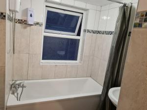a bathroom with a bath tub and a window at 4Br-2Ensuite-10minCentralLondon-Sleeps11-Parking in London