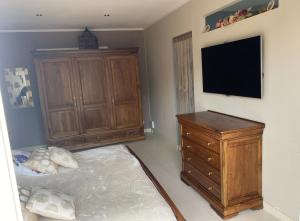 a bedroom with a bed and a dresser and a flat screen tv at La maison du Bonheur 34 in Florensac