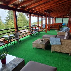 a screened in porch with green flooring and tables and chairs at Vila Ozon in Ranca