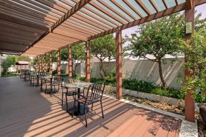 a wooden deck with tables and chairs under a pergola at Somerset Hoa Binh Hanoi in Hanoi