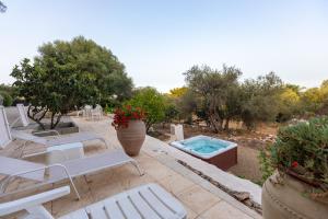 Un patio con sillas blancas y una piscina. en Casale Antiche Mura Siracusa, en Siracusa