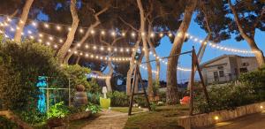a woman sitting in a garden under a string of lights at Villa Pavone in Ginosa Marina