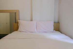a bed with white sheets and two pillows at Good Choice 2BR at 12th Floor Gateway Ahmad Yani Cicadas Apartment By Travelio in Bandung