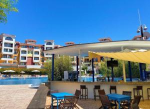 eine Terrasse mit Tischen und Stühlen neben einem Pool in der Unterkunft Victoria's apartments -Marina Cape - Aheloy in Aheloy
