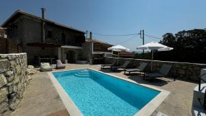 a swimming pool with two chairs and a house at Villa Vista in Asprogerakata