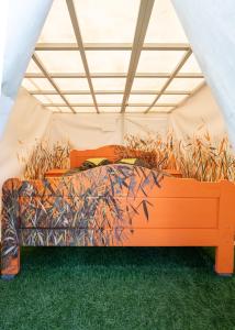 an orange bed in a tent with tall grass at Garden Clamping in Tallinn