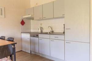 a kitchen with white cabinets and a sink at Beach appartement 40 in Callantsoog +12 photos